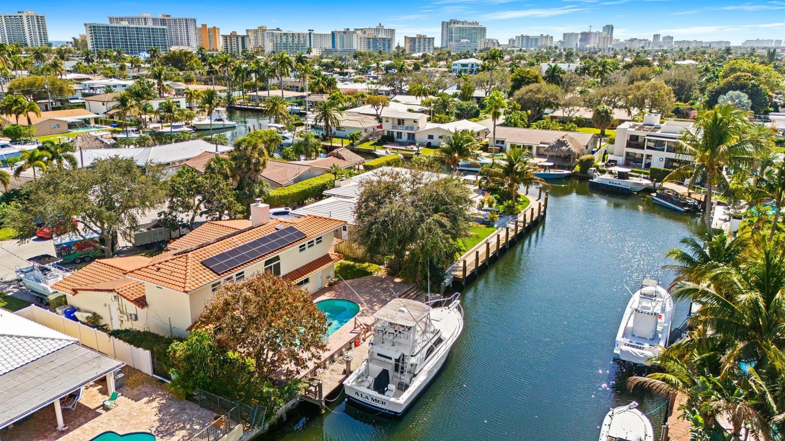 An aerial view of a waterfront house with a pool, solar panels, and docked boats — 1031 NE 27th Avenue, Pompano Beach FL 33062, POMPANO BEACH, FL