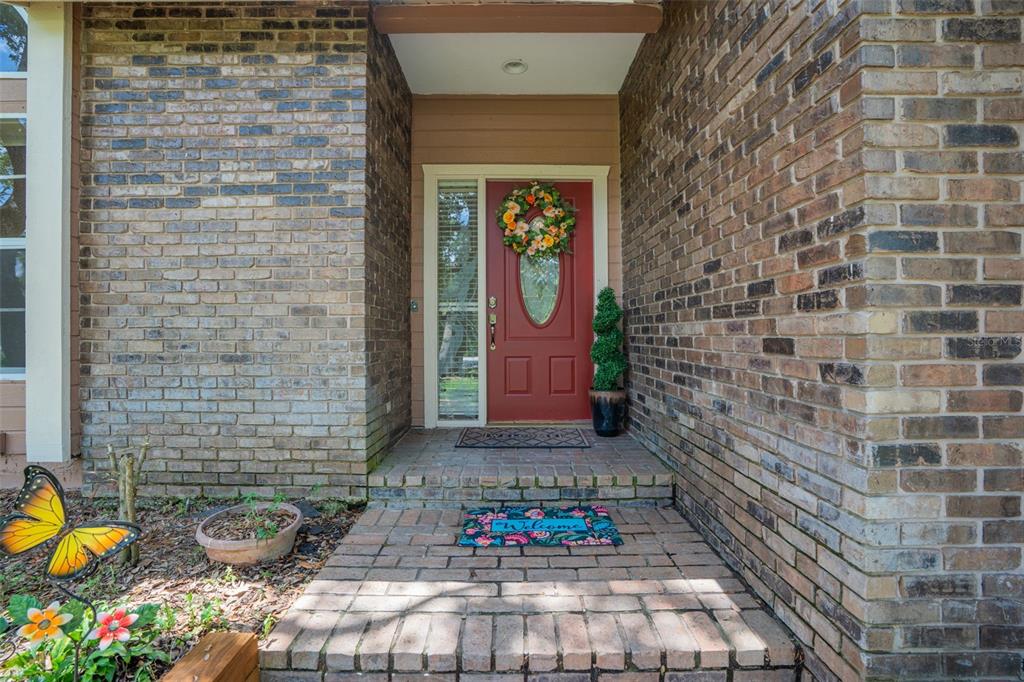 A brick-front entryway features a red front door with a wreath and a welcome mat — 6253 MURIWOOD COURT, SARASOTA, FL
