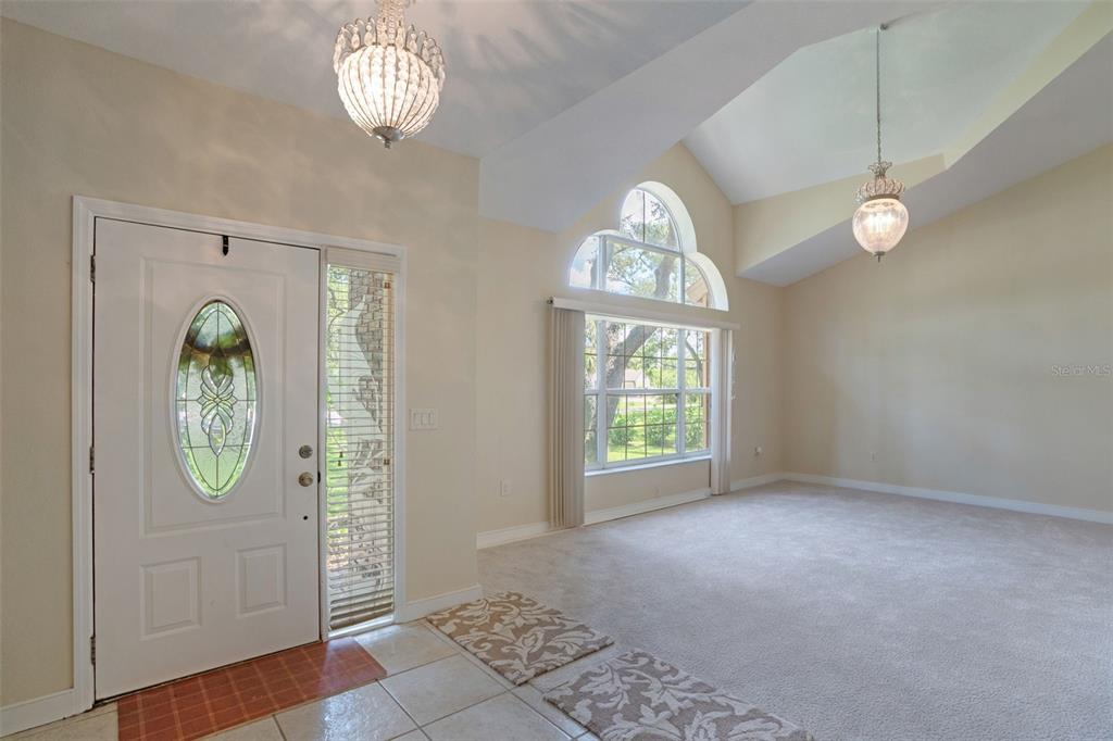 An entryway with a white front door, tile flooring, and a carpeted living area beyond — 6253 MURIWOOD COURT, SARASOTA, FL
