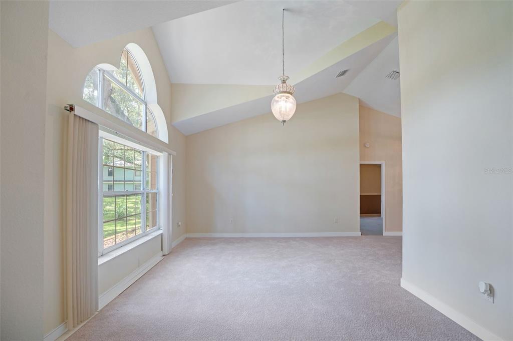 A living room with vaulted ceilings, beige carpet, and a large arched window — 6253 MURIWOOD COURT, SARASOTA, FL