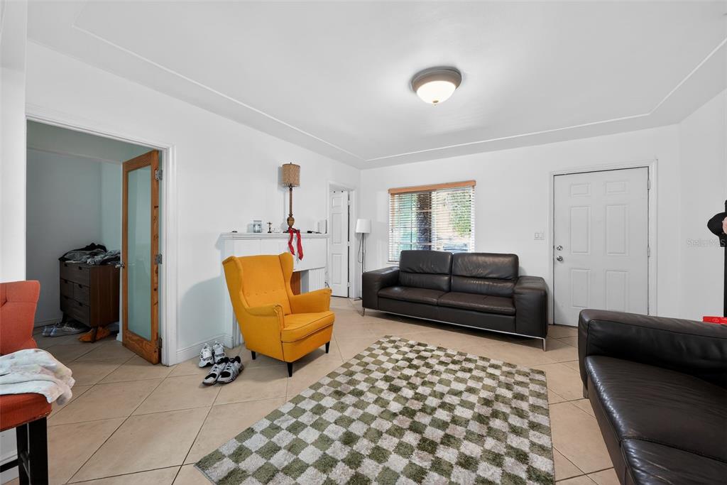 A living room features tile flooring, a yellow armchair, two dark sofas, and a rug — 2131 BIARRITZ DRIVE, MIAMI BEACH, FL