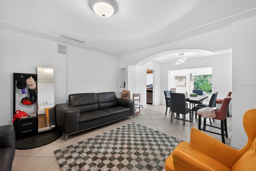 A living room with a black leather sofa, checkered rug, and an adjacent dining area — 2131 BIARRITZ DRIVE, MIAMI BEACH, FL