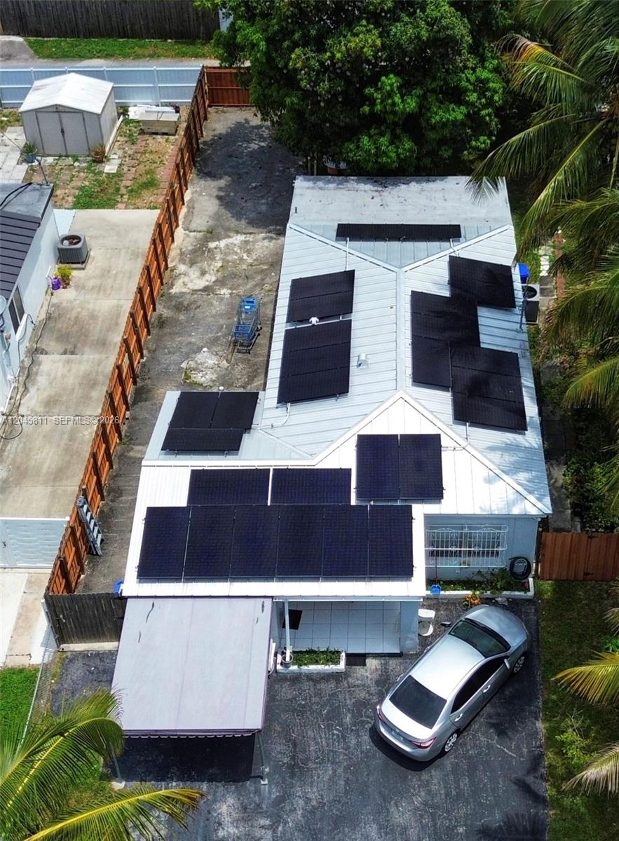 An aerial view shows a house with a metal roof covered in numerous solar panels — 1445 NE 174th St, North Miami Beach FL 33162, NORTH MIAMI BEACH, FL