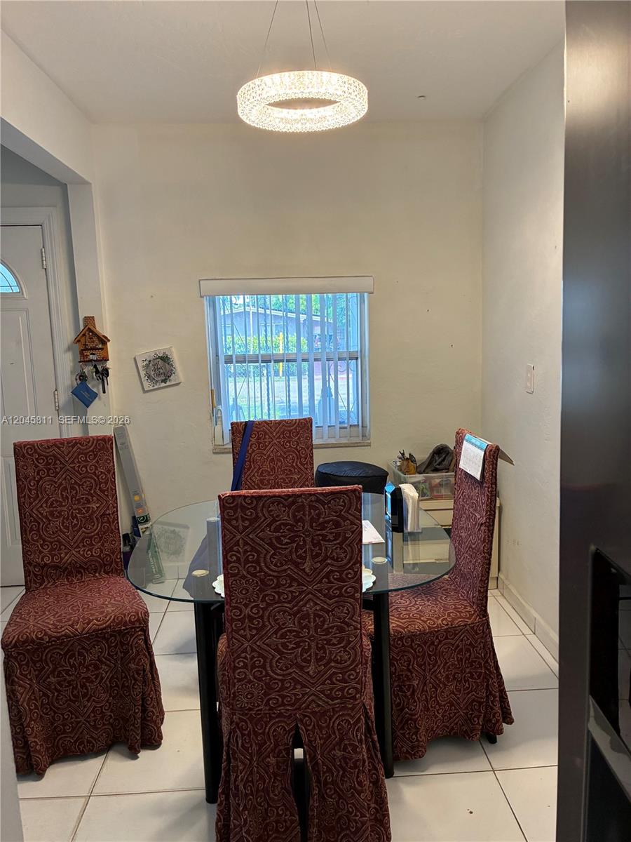 A dining area features a glass-topped table with four patterned chairs under a crystal chandelier — 1445 NE 174th St, North Miami Beach FL 33162, NORTH MIAMI BEACH, FL