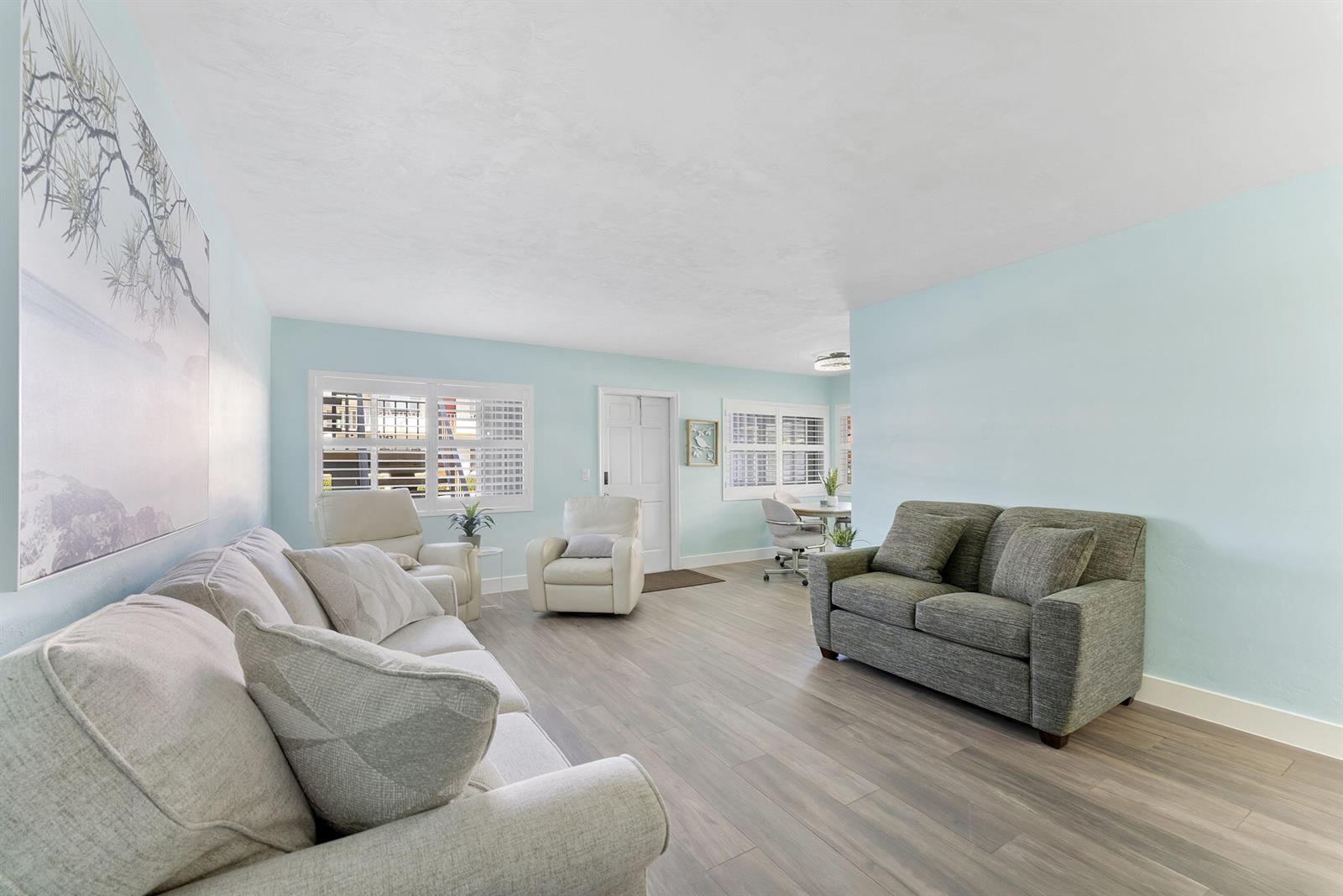 A living room features light blue walls, wood-look flooring, and a mix of seating furniture — 3322 Cynthia Lane # 102, FL 33461, FL