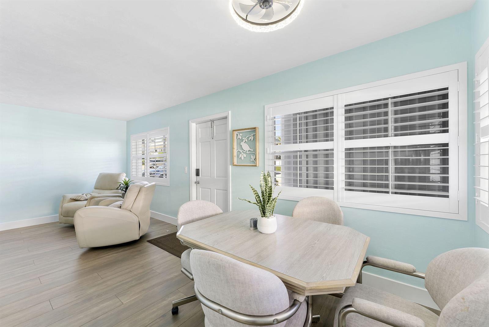 A dining area with a light wood table and chairs sits next to a living space — 3322 Cynthia Lane # 102, FL 33461, FL