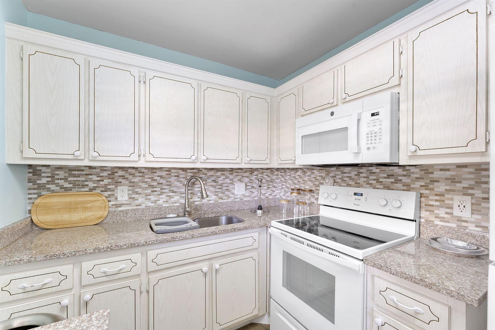 A kitchen with white cabinets, granite countertops, a tiled backsplash, and white appliances — 3322 Cynthia Lane # 102, FL 33461, FL