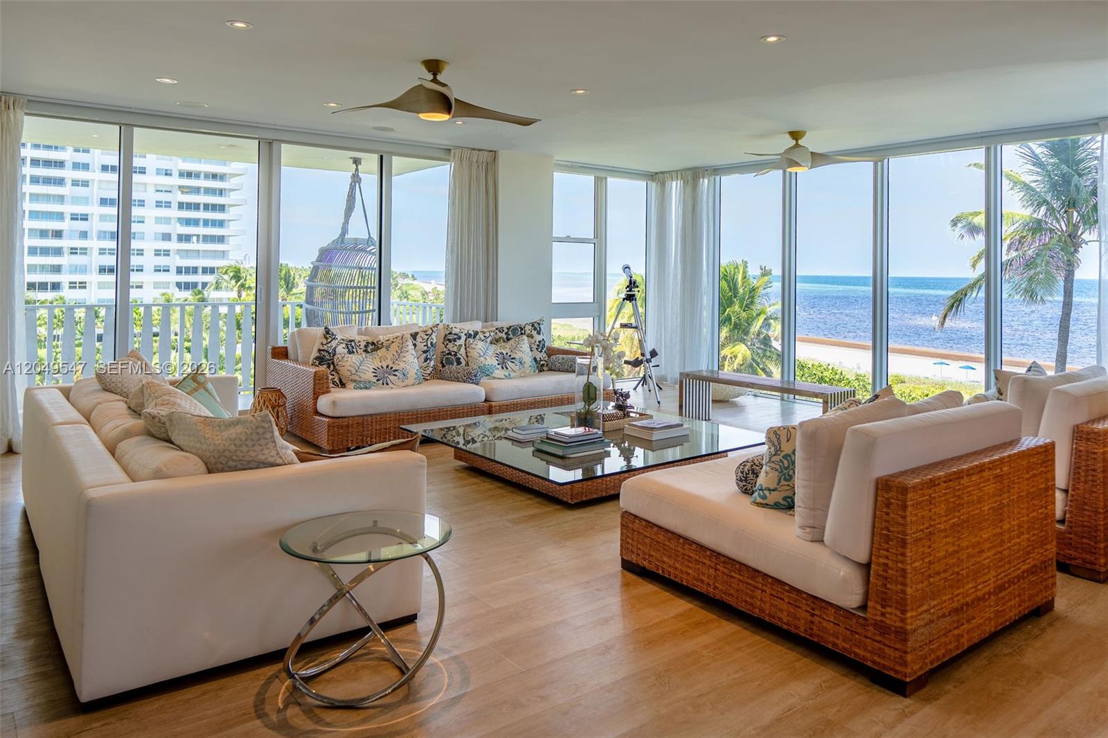 A bright living room features wicker-framed sofas, a glass coffee table, and floor-to-ceiling ocean views — 200 Ocean Lane Dr # 501, Key Biscayne FL 33149, KEY BISCAYNE, FL