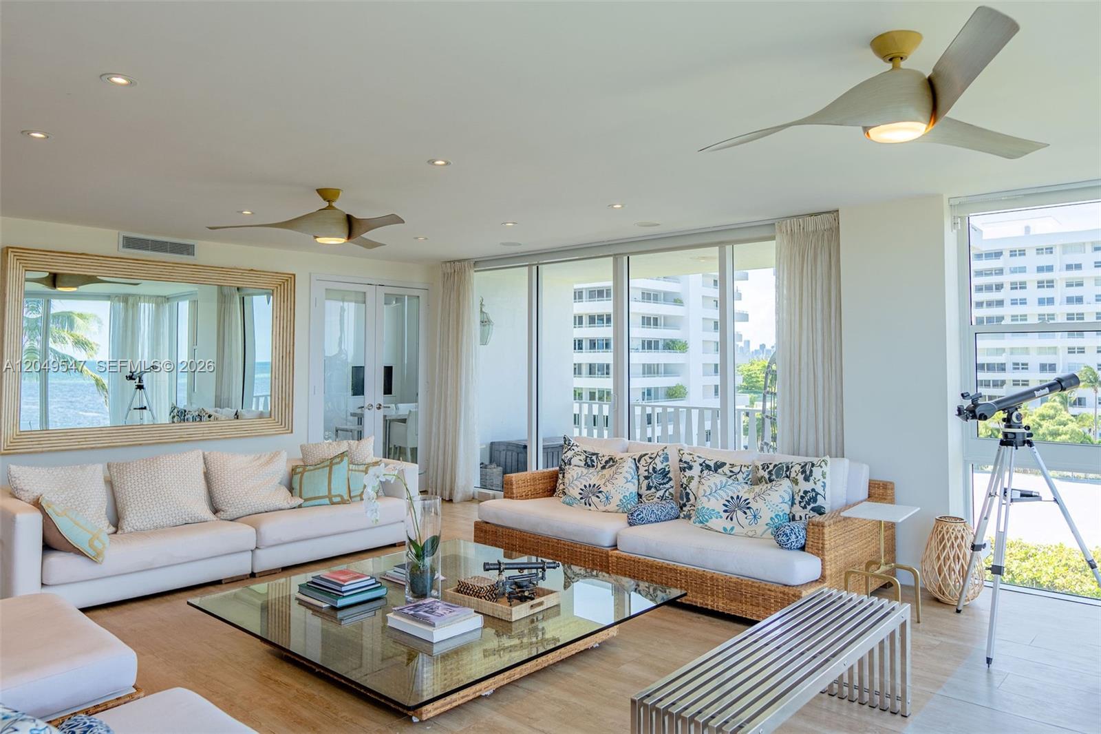 A bright living room features two sofas, a glass coffee table, and floor-to-ceiling windows — 200 Ocean Lane Dr # 501, Key Biscayne FL 33149, KEY BISCAYNE, FL