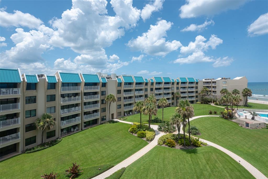 An exterior view of a multi-story beachfront condominium complex with balconies overlooking a landscaped lawn — 4501 S ATLANTIC AVENUE UNIT 5090, NEW SMYRNA BEACH, FL