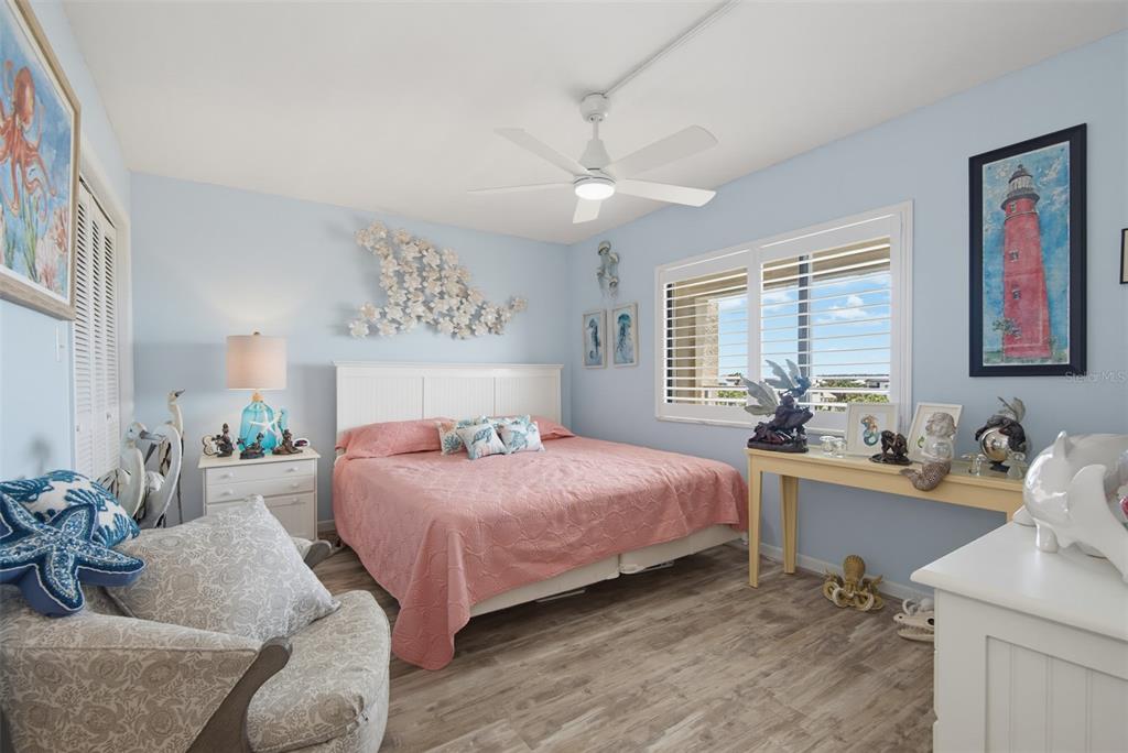 A bedroom features light blue walls, a pink bedspread, a ceiling fan, and coastal decor — 4501 S ATLANTIC AVENUE UNIT 5090, NEW SMYRNA BEACH, FL