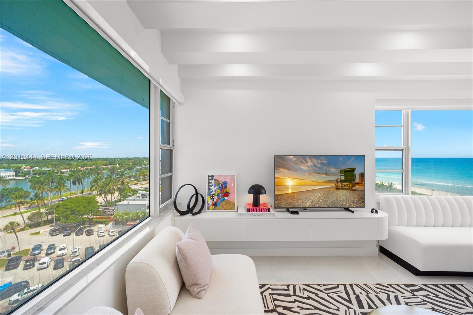 A bright living room features a floating white console, a television, and panoramic ocean views — 5255 Collins Ave # 8F, Miami Beach FL 33140, MIAMI BEACH, FL