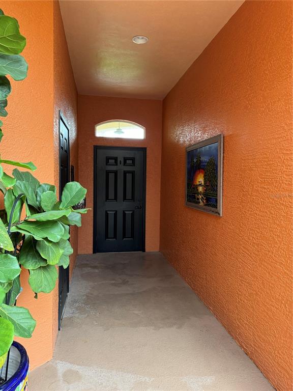 An outdoor entryway features orange textured walls, a black front door, and a potted plant — 8636 VILLANOVA DRIVE UNIT 1201, CAPE CANAVERAL, FL