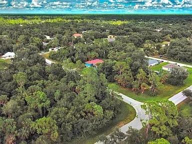 An aerial view shows a residential neighborhood with houses surrounded by dense trees and roads — 145 LOFTIN STREET, PORT CHARLOTTE, FL