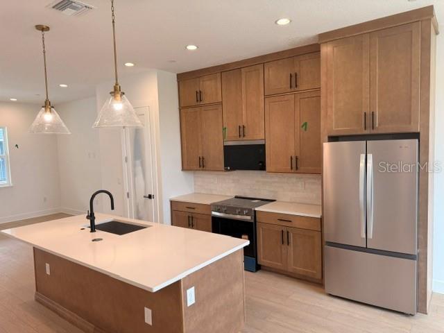 A kitchen features light wood cabinets, a white island countertop, and stainless steel appliances — 9301 LUMINARY BOULEVARD, ORLANDO, FL