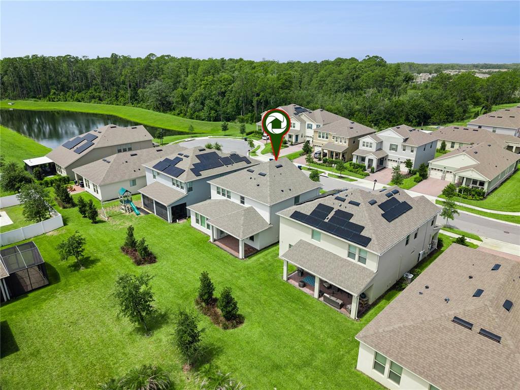 An aerial view shows several suburban houses with solar panels and backyards near a pond — 11031 JACKSON COVE, WINTER GARDEN, FL