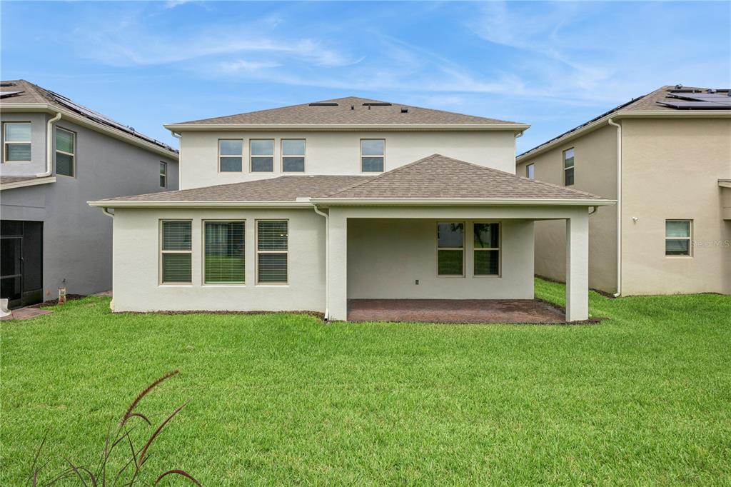 The rear exterior of a two-story house features a covered patio and a grassy lawn — 11031 JACKSON COVE, WINTER GARDEN, FL