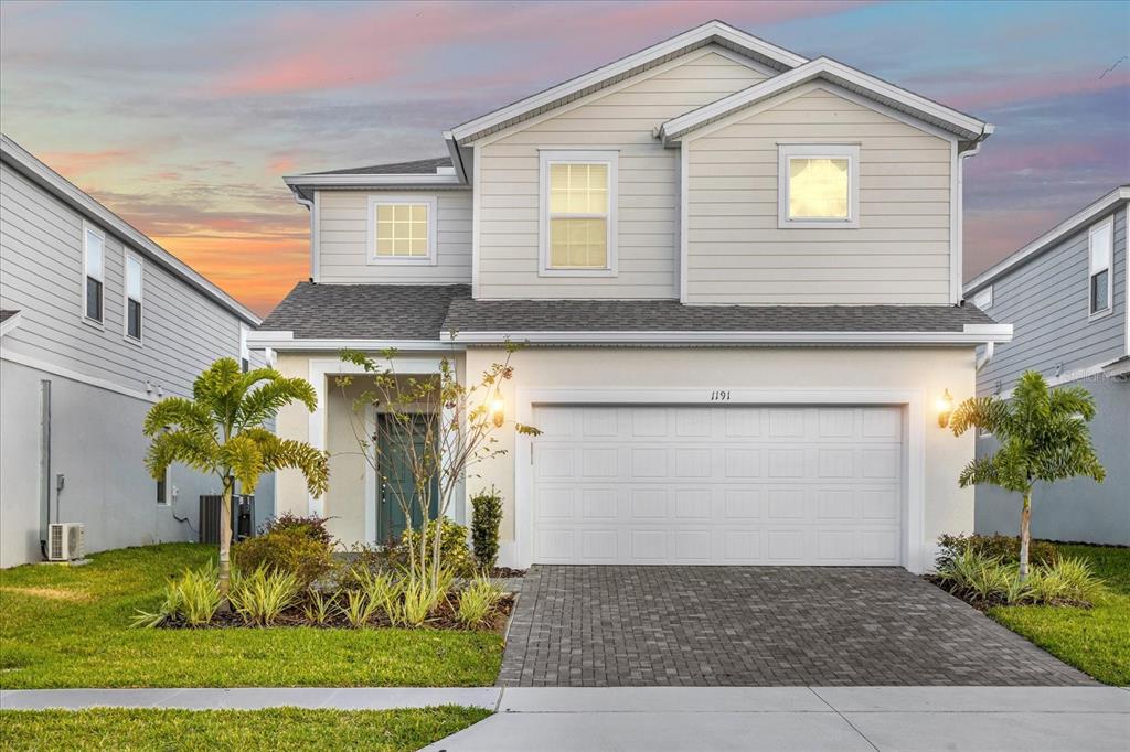 A two-story suburban house features light-colored siding, a two-car garage, and a paved driveway — 1191 ALOHA BOULEVARD, DAVENPORT, FL