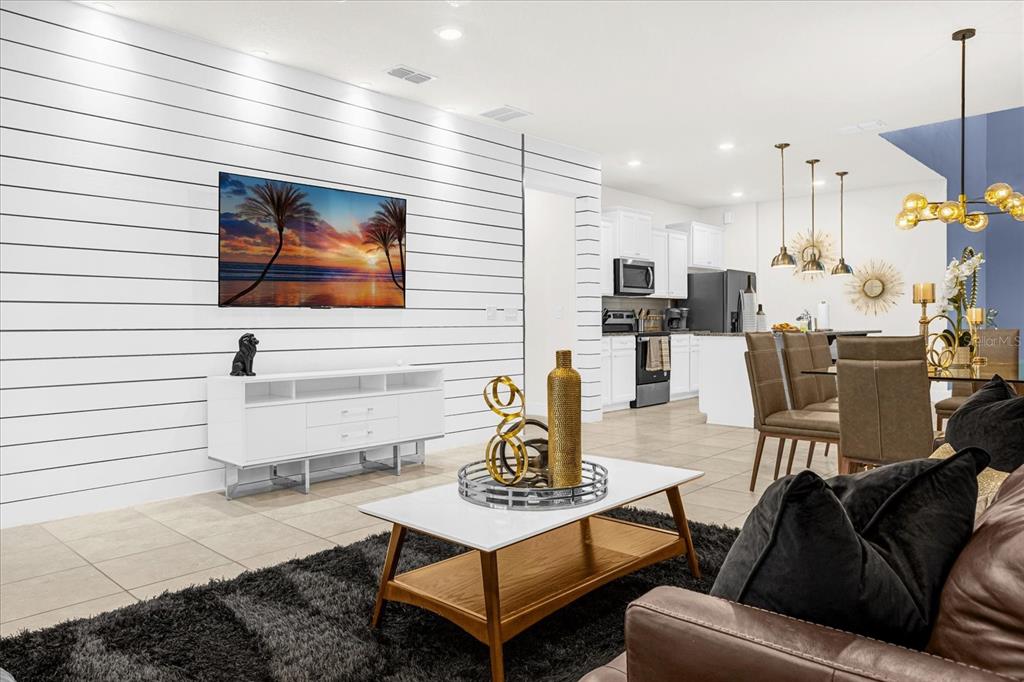 A living room with a shiplap accent wall, white media console, and an open kitchen — 1191 ALOHA BOULEVARD, DAVENPORT, FL