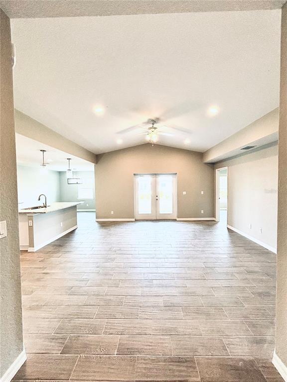 An open-concept living area features vaulted ceilings, tile flooring, and a kitchen with a peninsula — 415 BAYTREE DRIVE, ROTONDA WEST, FL