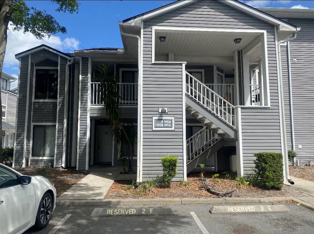 A two-story apartment building with gray siding, an exterior staircase, and reserved parking spaces — 2227 STONINGTON AVENUE UNIT 2227, ORLANDO, FL
