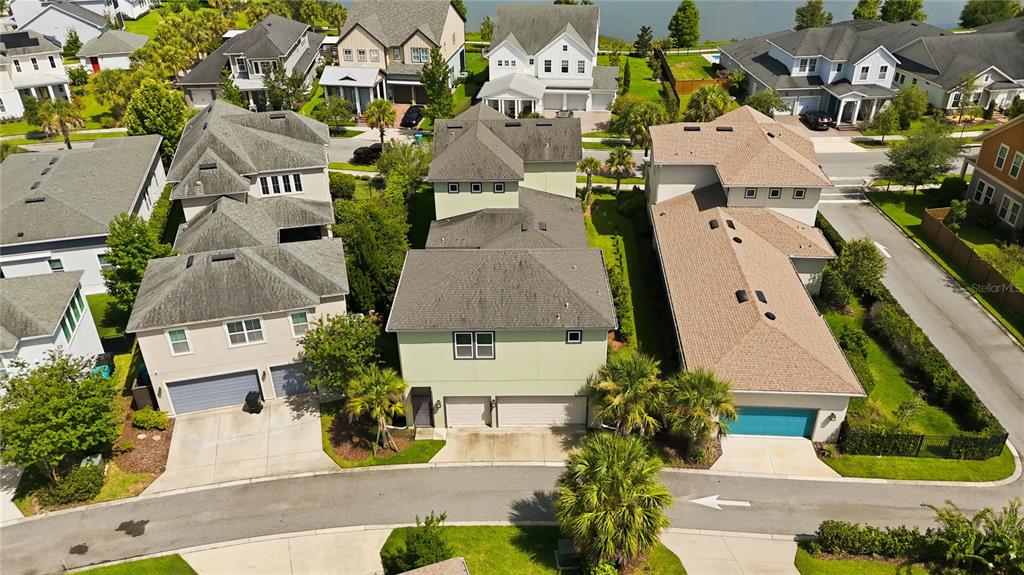 An aerial view shows three suburban houses with gray roofs and driveways along a street — 13030 STODDART AVENUE, ORLANDO, FL