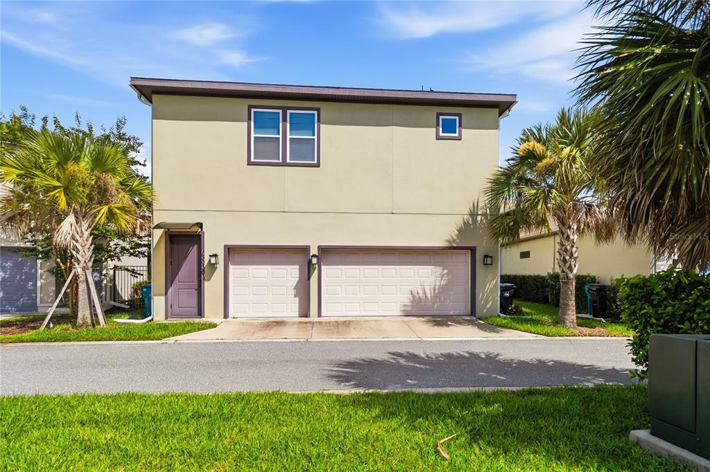 A two-story building exterior features a double garage, a single door, and a large window — 13030 STODDART AVENUE, ORLANDO, FL