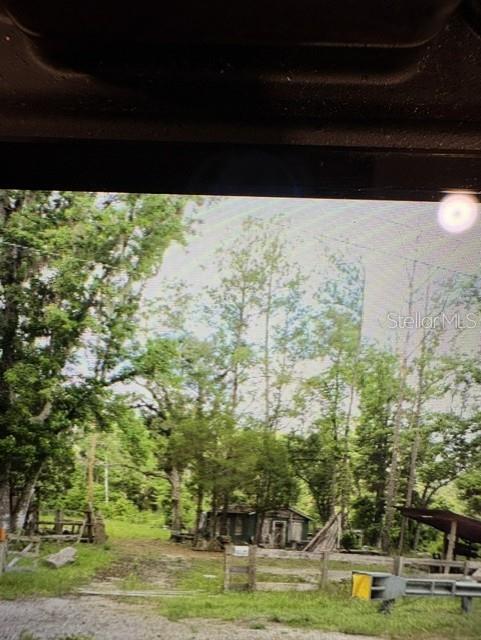 A small, weathered wooden cabin sits in a clearing surrounded by dense green trees — COUNTY ROAD 305, BUNNELL, FL