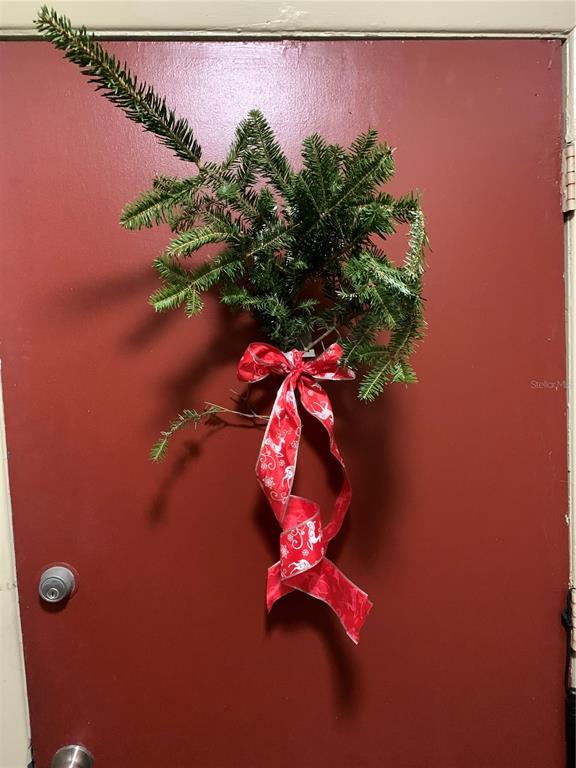 A red door features a holiday evergreen swag decoration tied with a red patterned ribbon — 1799 N HIGHLAND AVENUE UNIT 170, CLEARWATER, FL