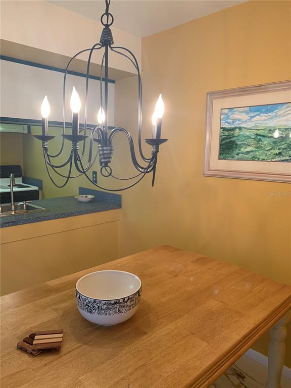 A dining area features a wooden table, a black chandelier, and a framed landscape painting — 1799 N HIGHLAND AVENUE UNIT 170, CLEARWATER, FL