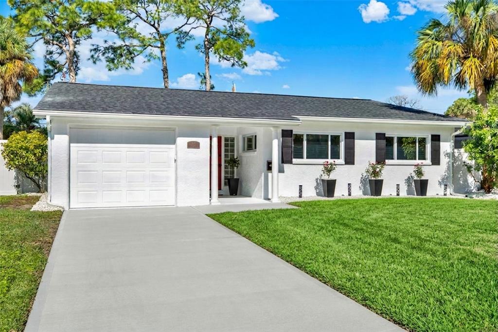 A white single-story house with a garage, a concrete driveway, and a green lawn — 4510 NE HELENA STREET NE, ST PETERSBURG, FL