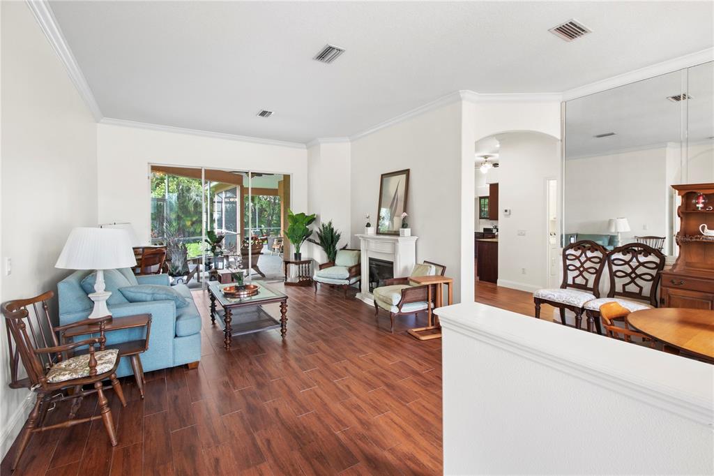 A living room with wood-look tile floors, a fireplace, and a sliding door to a lanai — 7341 FEATHERSTONE BOULEVARD, SARASOTA, FL