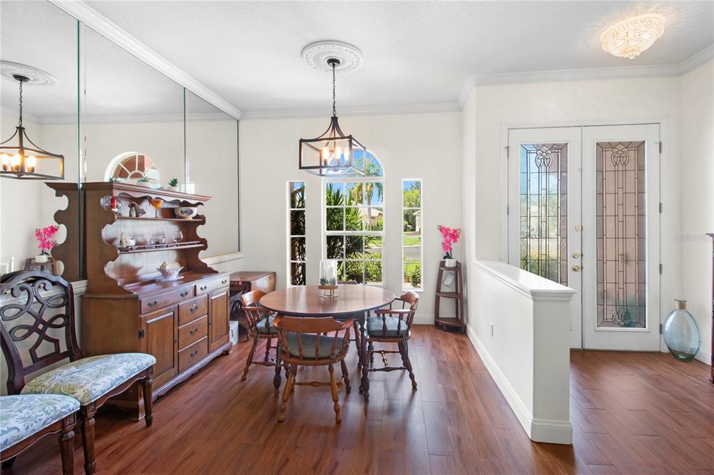 A dining room with wood floors, a hutch, a round table, and a glass-paneled door — 7341 FEATHERSTONE BOULEVARD, SARASOTA, FL
