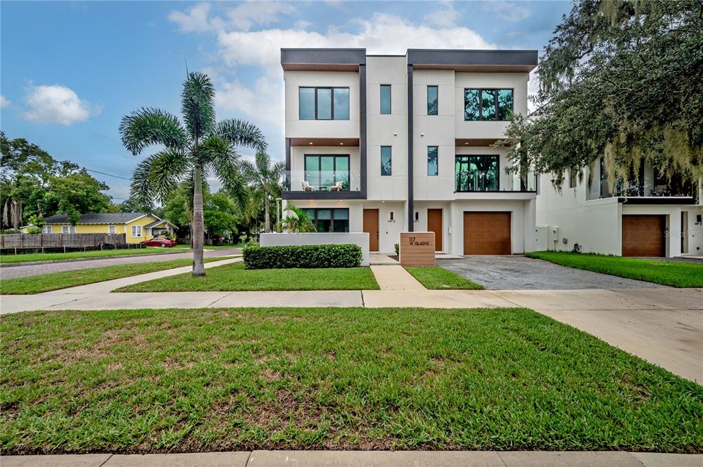 A modern three-story duplex with white stucco siding, flat roofs, and attached garages — 117 W GLADYS STREET UNIT 2, TAMPA, FL