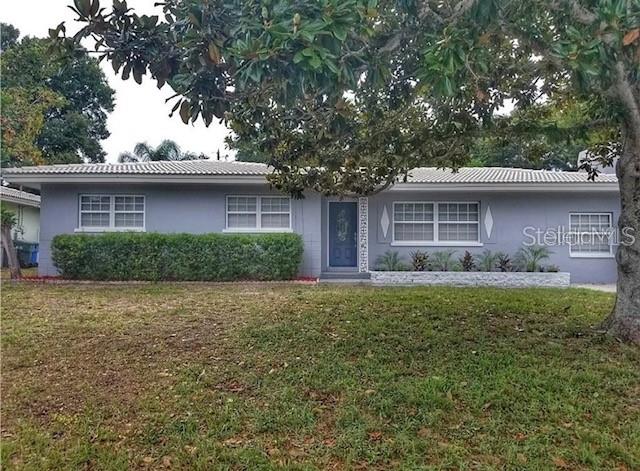 A single-story gray house features a tiled roof, a central front door, and manicured landscaping — 1664 S EVERGREEN AVENUE, CLEARWATER, FL
