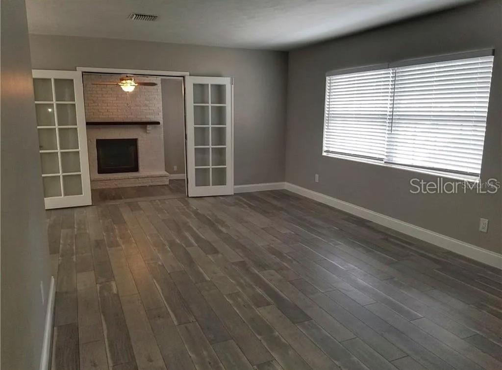 A living room with gray walls, wood-look flooring, and French doors leading to a fireplace — 1664 S EVERGREEN AVENUE, CLEARWATER, FL