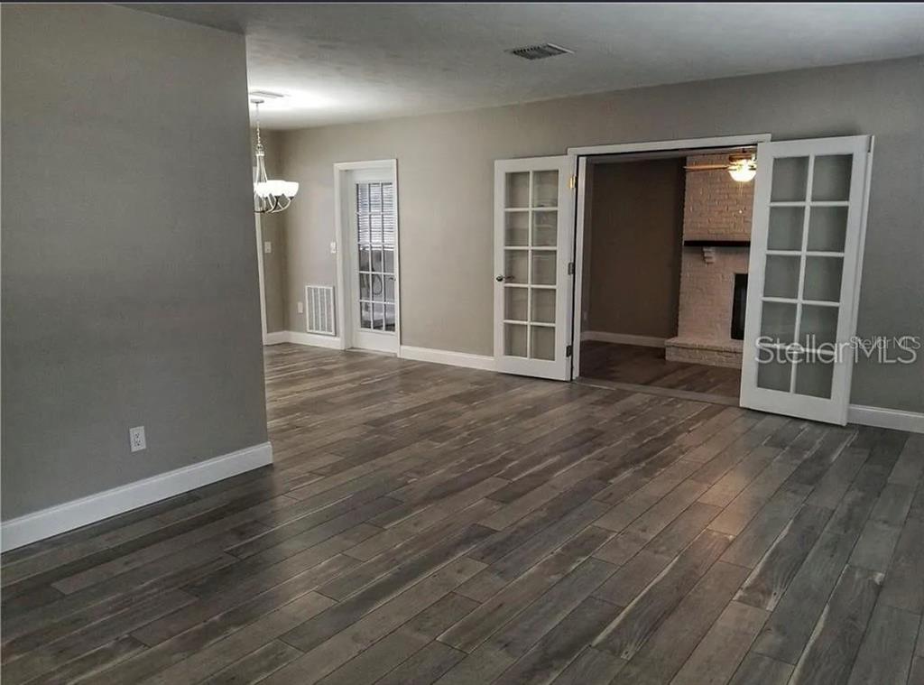 A room with gray walls, wood-look flooring, and French doors leading to a fireplace room — 1664 S EVERGREEN AVENUE, CLEARWATER, FL