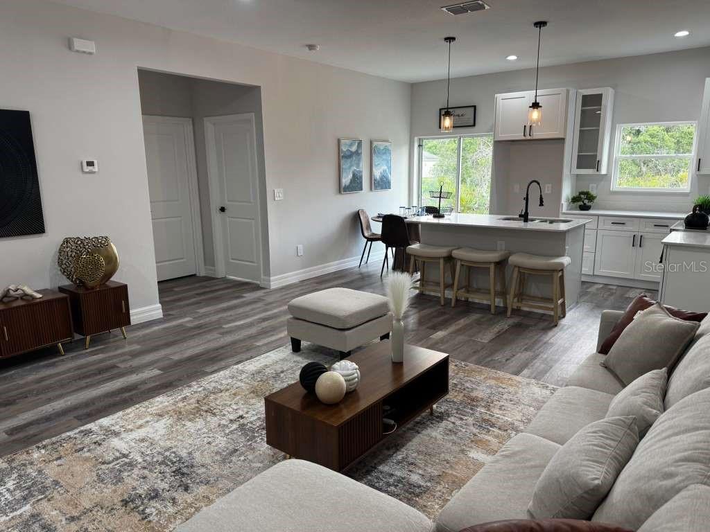 An open-concept living room and kitchen featuring light wood-look flooring and a central island — 300 CASPIAN TERN AVENUE, SEBRING, FL