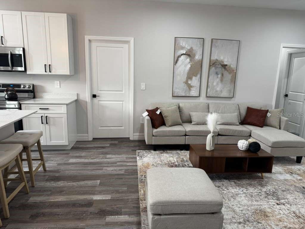 A living room with a sectional sofa, coffee table, and adjacent kitchen with white cabinets — 300 CASPIAN TERN AVENUE, SEBRING, FL