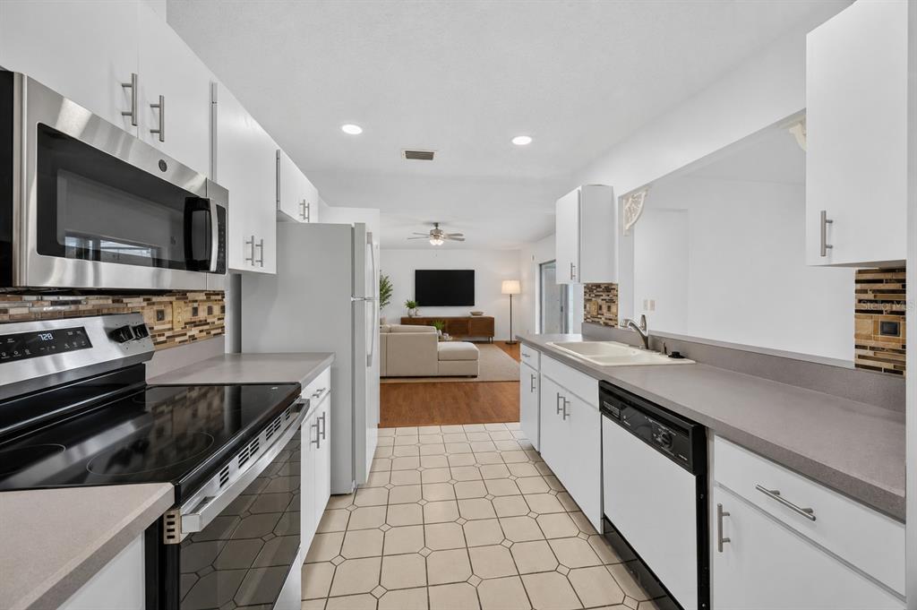 A galley kitchen features white cabinets, stainless steel appliances, and a tiled floor — 6510 11TH AVENUE W, BRADENTON, FL