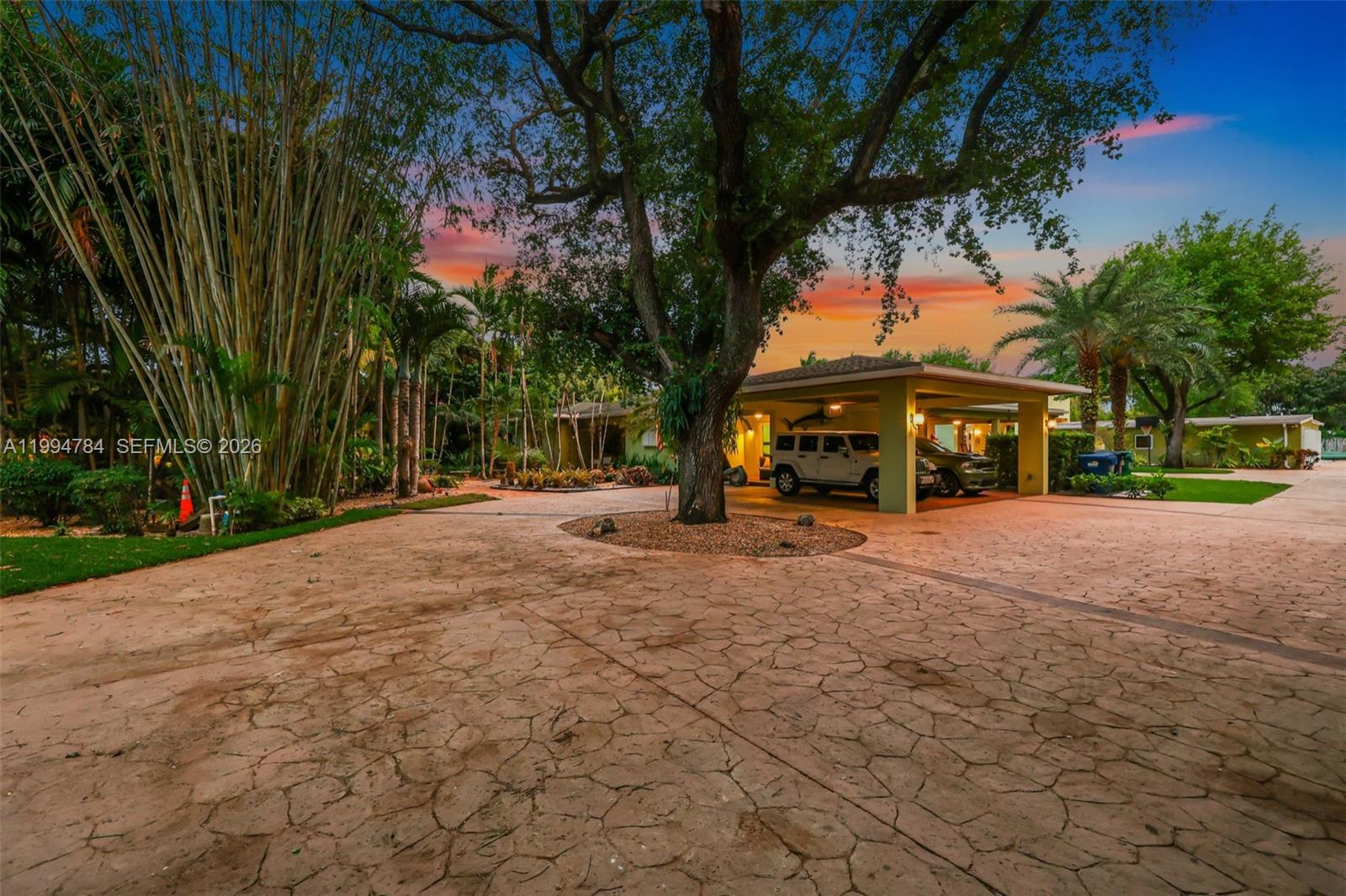 A driveway with a large tree leads to a house with a covered parking area — 9234 SW 112th St, Miami FL 33176, MIAMI, FL