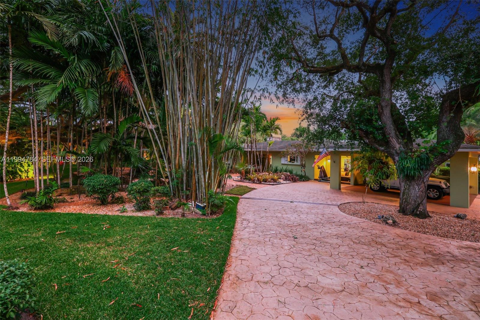 A paved driveway leads to a single-story house surrounded by lush trees and bamboo — 9234 SW 112th St, Miami FL 33176, MIAMI, FL