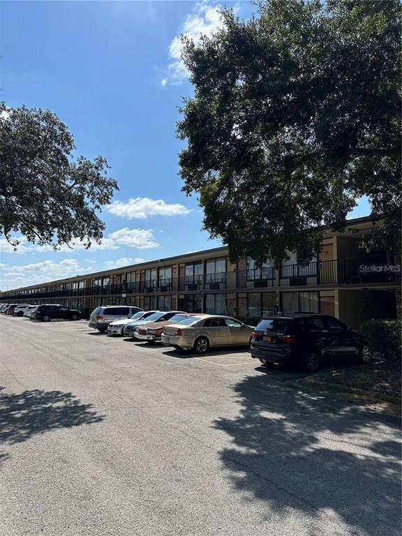 A multi-story apartment building with a parking lot in the foreground under a blue sky — 7900 S ORANGE BLOSSOM TRAIL UNIT 2065, ORLANDO, FL
