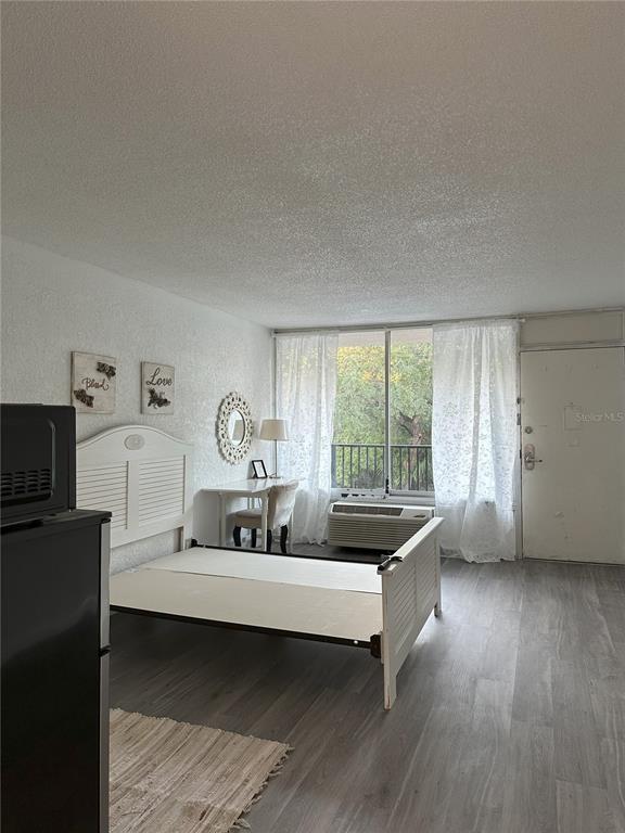 A studio apartment features a white bed frame, a small desk, and light wood flooring — 7900 S ORANGE BLOSSOM TRAIL UNIT 2065, ORLANDO, FL