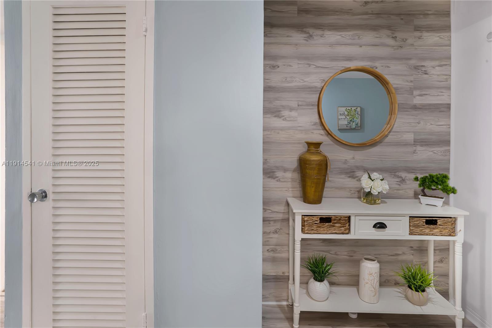A white console table sits against a wood-paneled wall with a round mirror above it — 100 Lincoln Rd # 607, Miami Beach FL 33139, MIAMI BEACH, FL