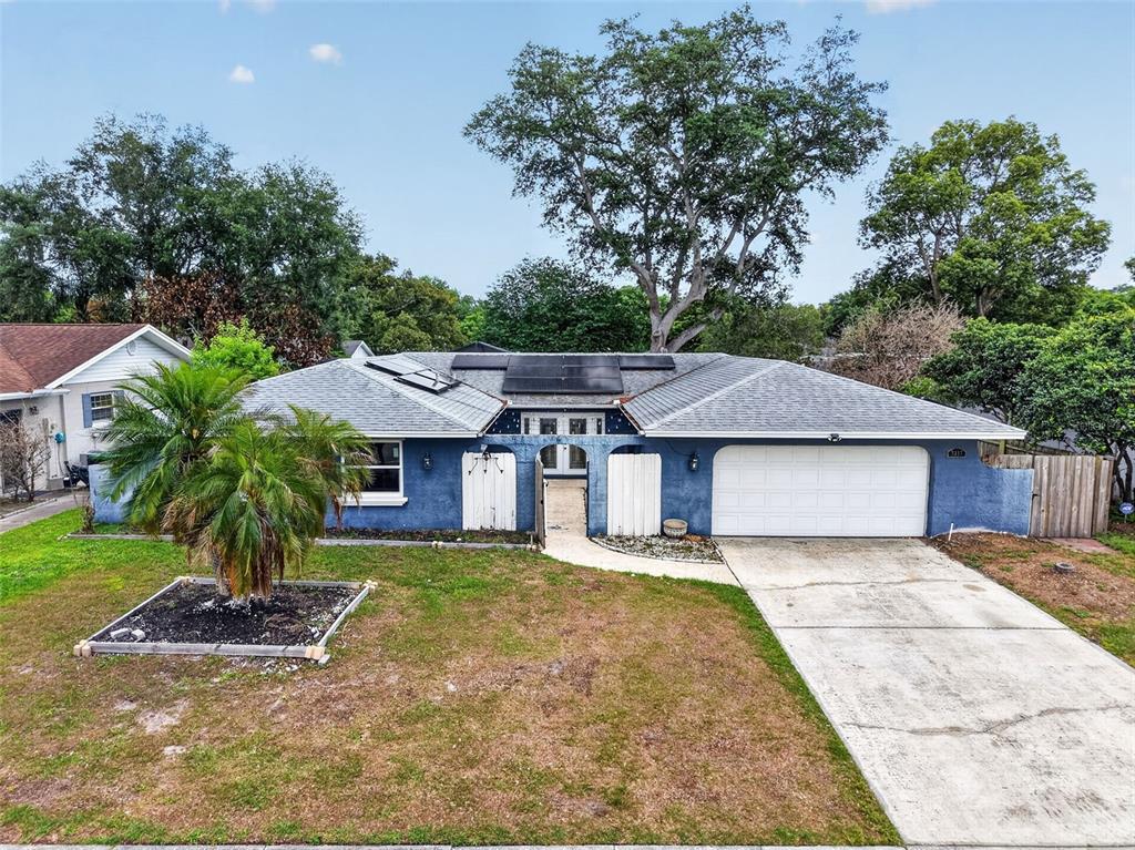 A blue single-story house with a white garage door, solar panels, and a front palm tree — 3217 LAKE ANDERSON AVENUE, ORLANDO, FL