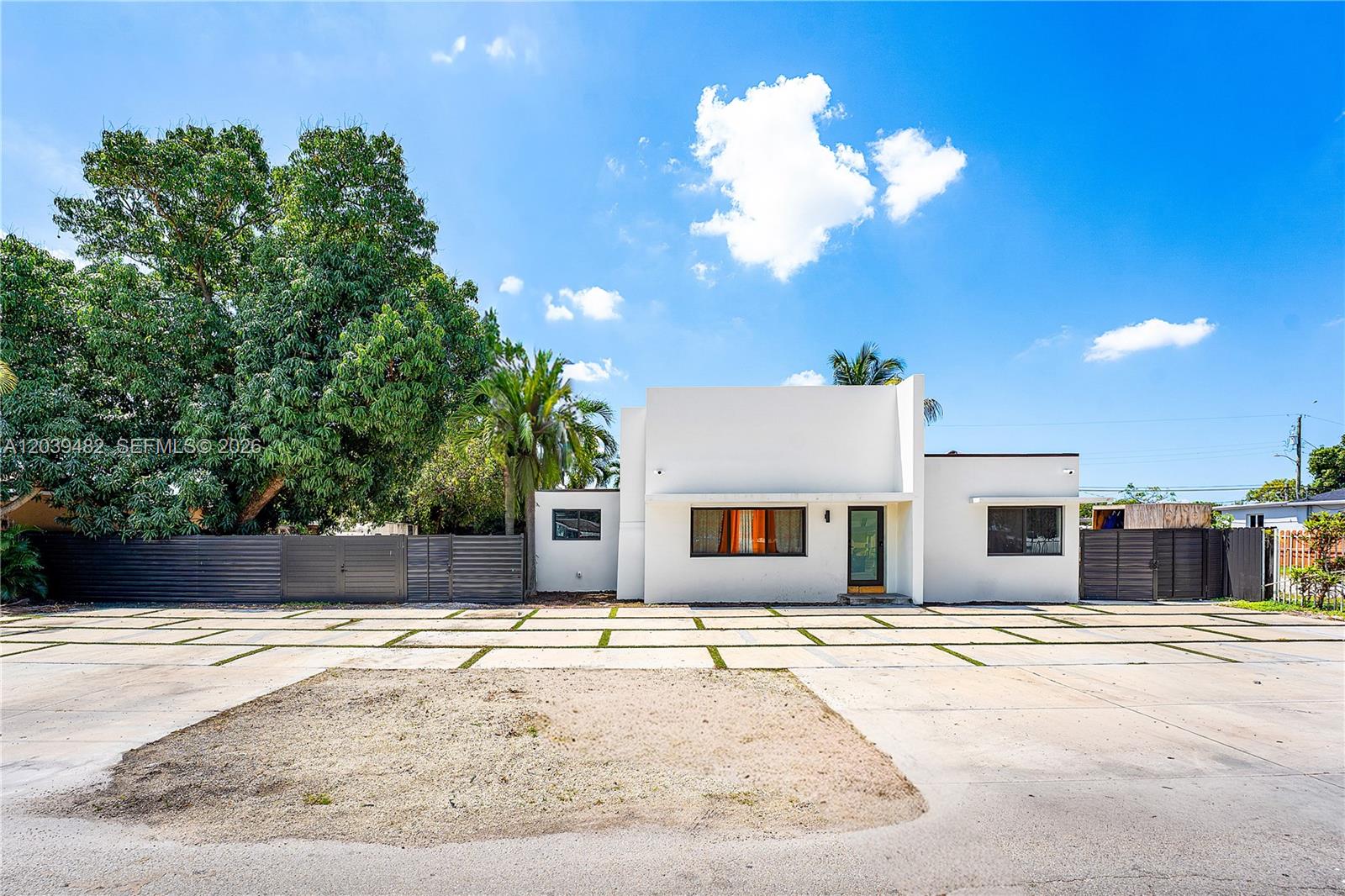 A white, modern single-story house features a large concrete driveway with grass strips — 3040 NW 93rd St, Miami FL 33147, MIAMI, FL