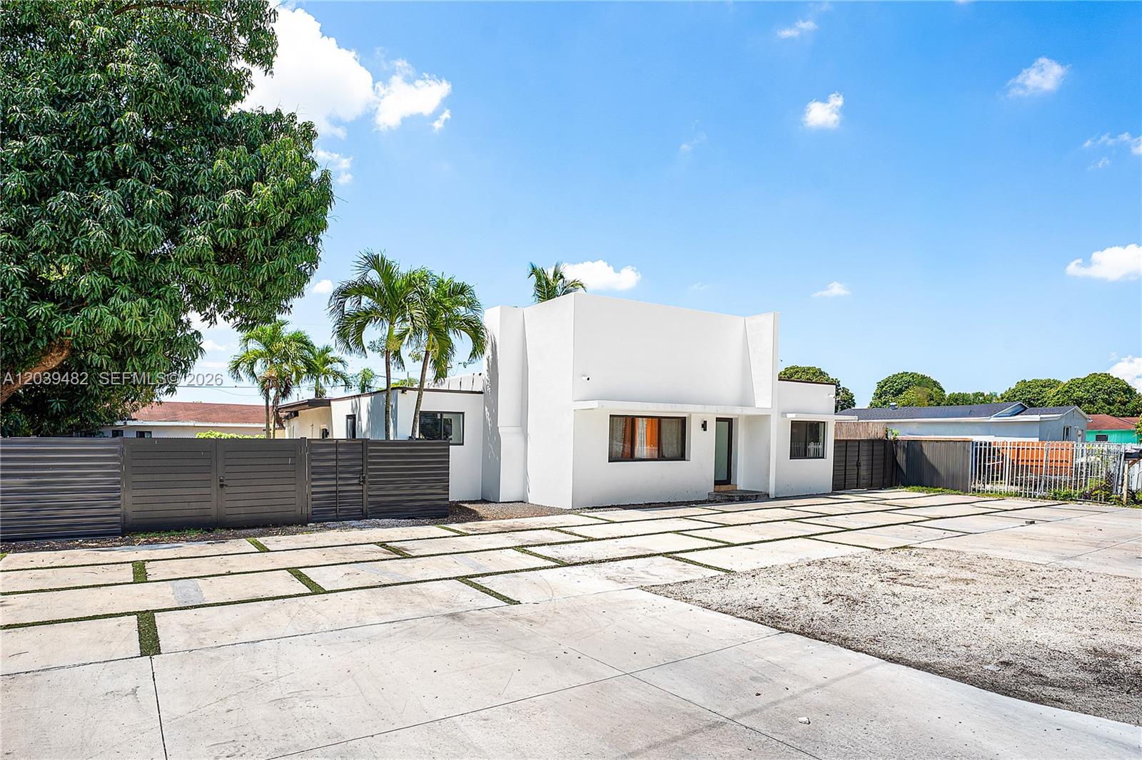 A white, flat-roofed house features a large concrete driveway with grass strips and palm trees — 3040 NW 93rd St, Miami FL 33147, MIAMI, FL