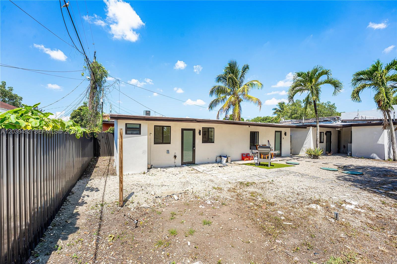 The exterior of a single-story house features a gravel yard, palm trees, and a fence — 3040 NW 93rd St, Miami FL 33147, MIAMI, FL
