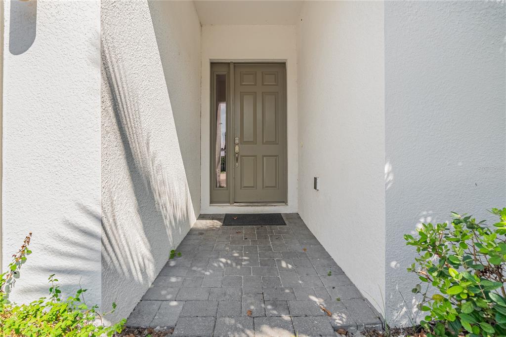 A front entryway features a gray door with a sidelight and a paved walkway — 4451 MONADO DRIVE, KISSIMMEE, FL